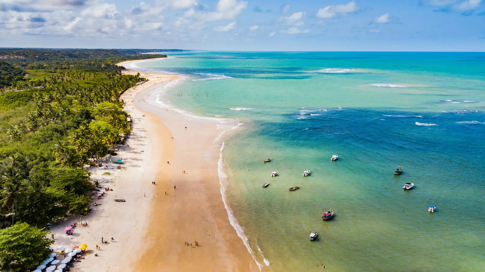 Vista aérea de praia com águas cristalinas e barcos